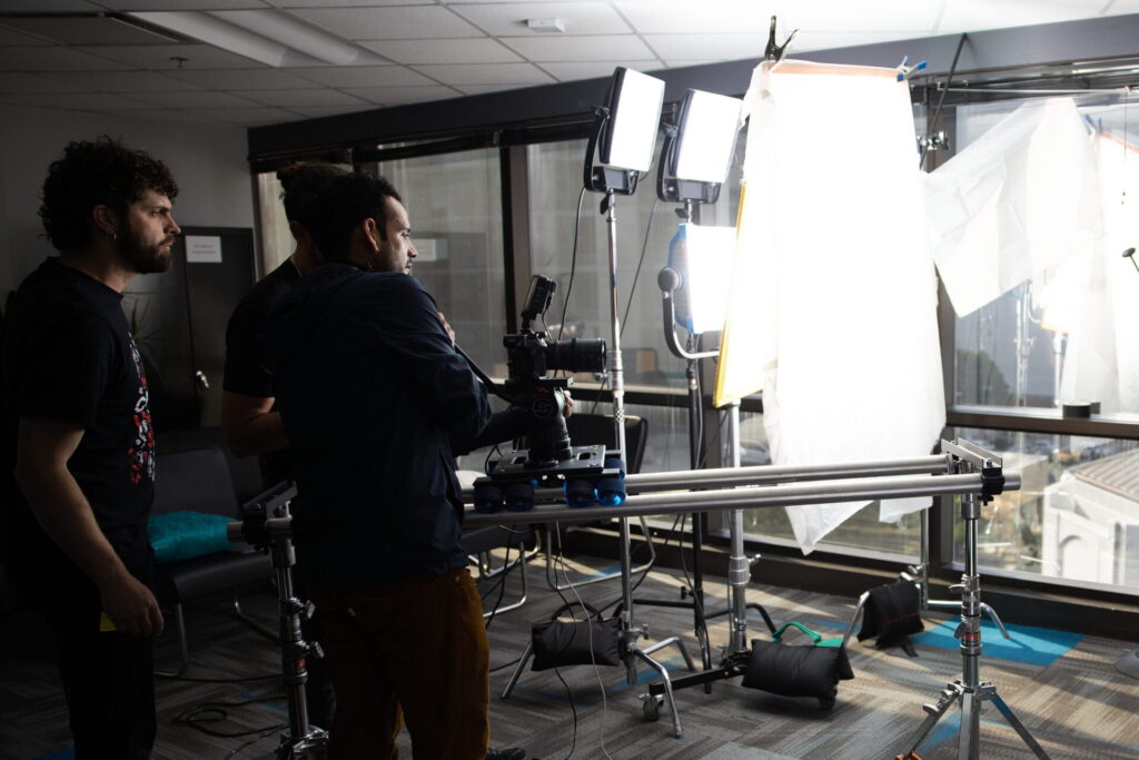 Video production crew setting up lighting for a technology company video shoot.